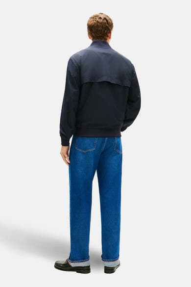 Veste bleue par TOMMY HILFIGER, vue de dos, portée avec un jean et des mocassins noirs.