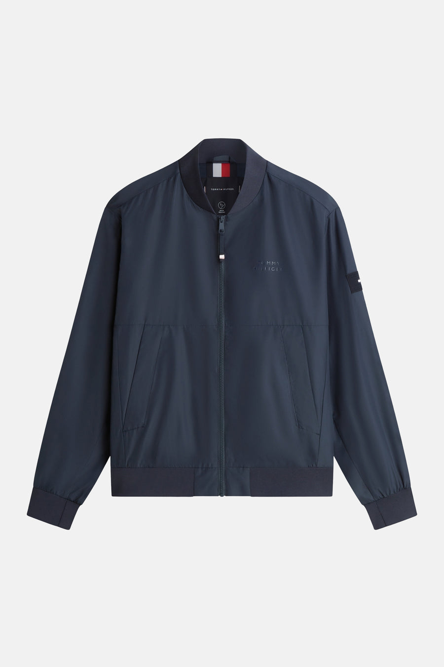 Veste bleue par TOMMY HILFIGER avec fermeture éclair sur un fond clair.