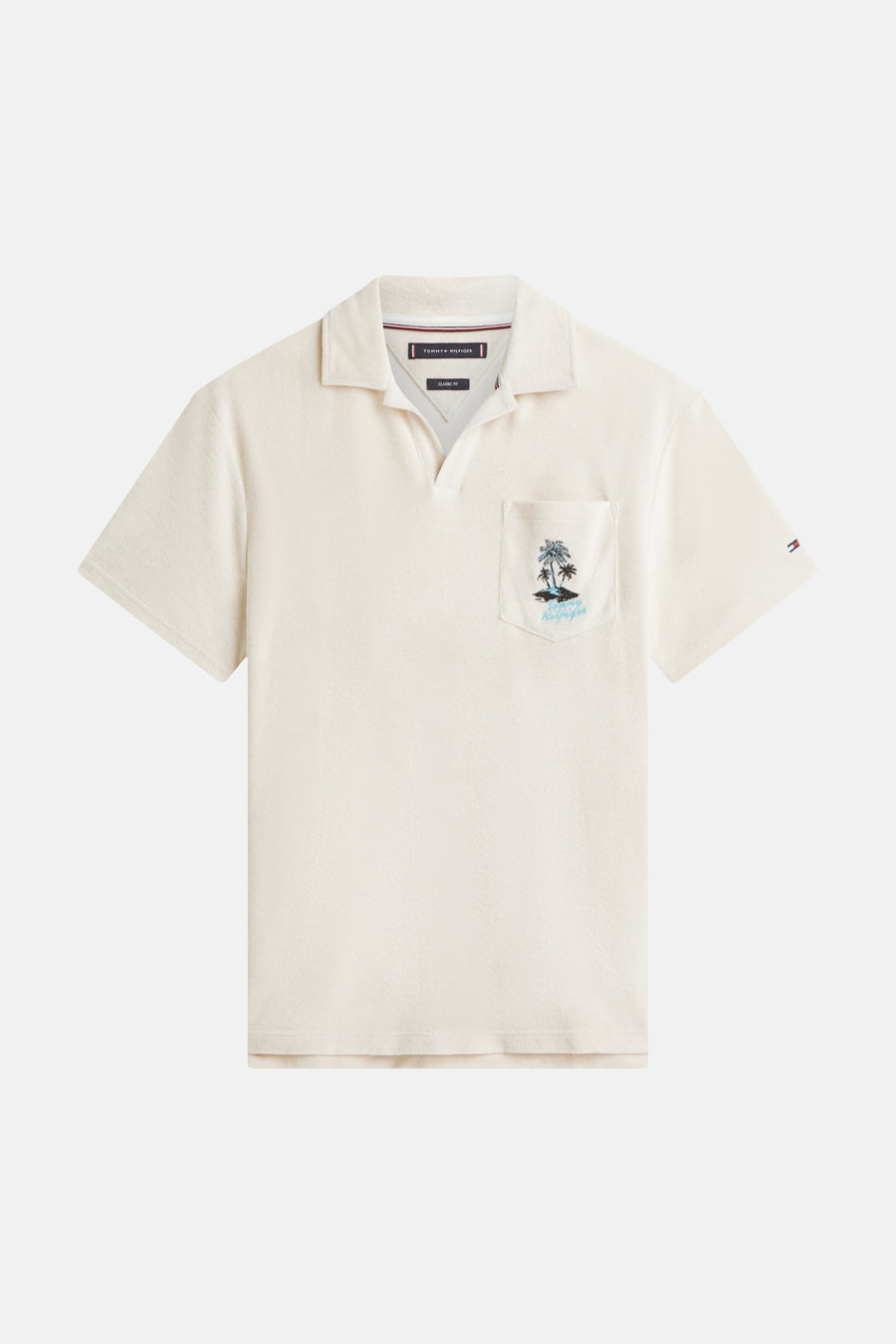 Polo écru en tissu éponge de TOMMY HILFIGER, brodé de palmiers et avec un petit logo sur la manche.