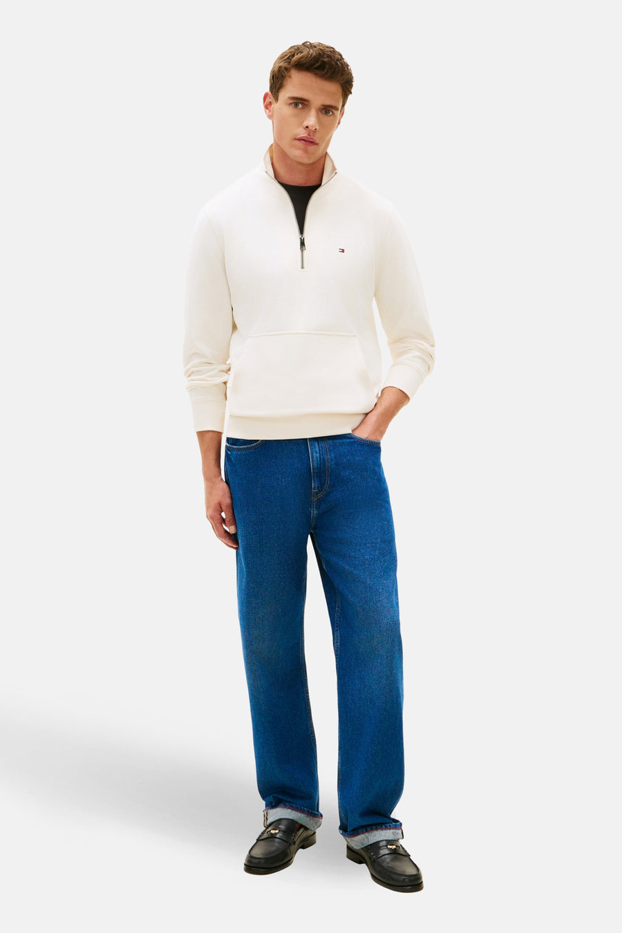 Sweat-shirt écru à col montant de Tommy Hilfiger, porté avec un jean bleu et des mocassins noirs.