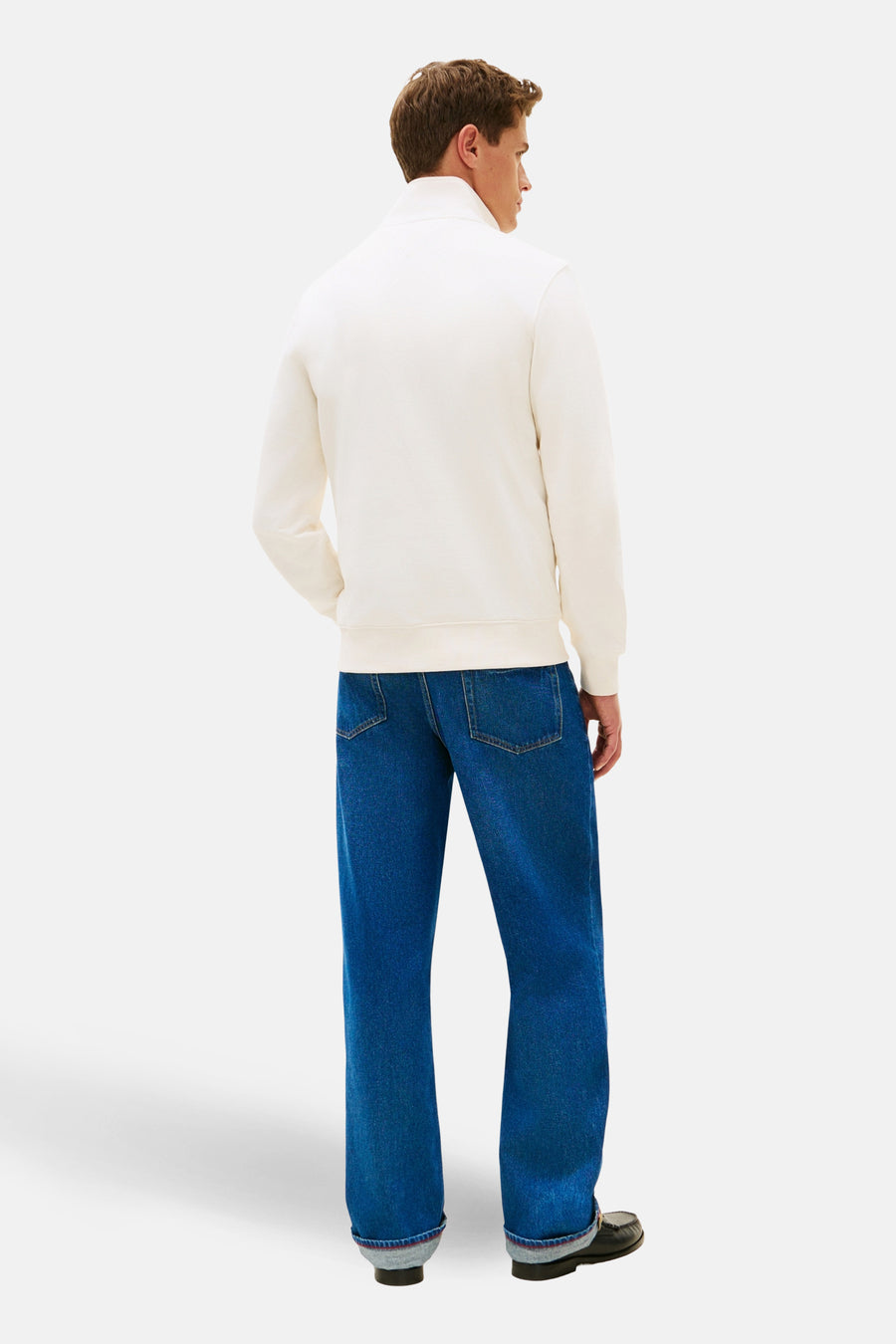 Sweat-shirt écru à col montant de TOMMY HILFIGER, porté avec un jean bleu ample et des mocassins noirs, vue arrière.
