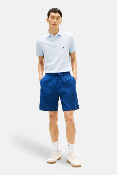 Bermuda bleu par Tommy Hilfiger, avec cordon de serrage et poches avant, porté avec un polo bleu clair.