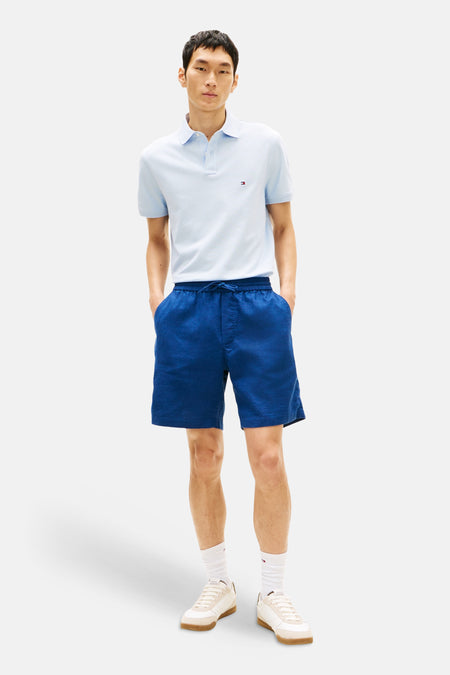 Bermuda bleu par Tommy Hilfiger, avec cordon de serrage et poches avant, porté avec un polo bleu clair.