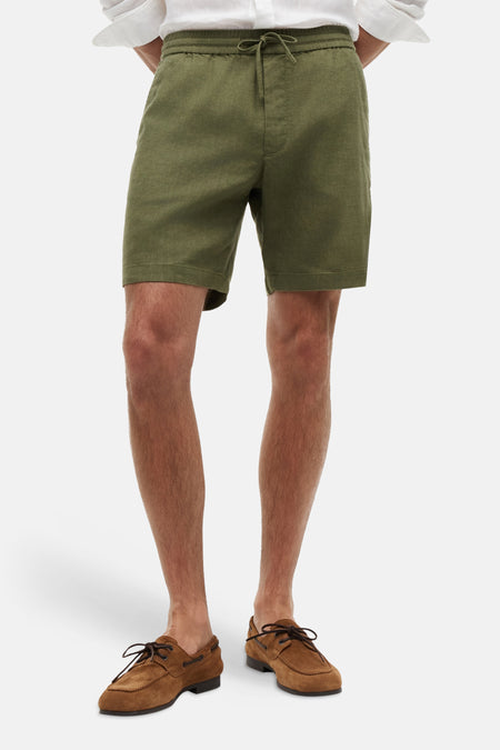 Groene bermuda van Tommy Hilfiger, gedragen met een wit overhemd en bruine bootschoenen.