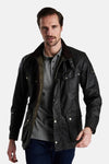 Imperméable kaki par BARBOUR, porté ouvert sur un polo gris, avec un col en velours côtelé.
