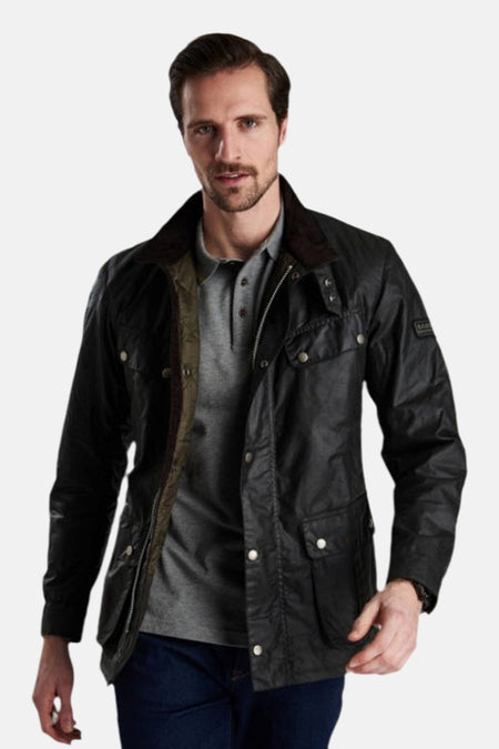 Kaki regenjas van BARBOUR, open gedragen over een grijs poloshirt, met een corduroy kraag.