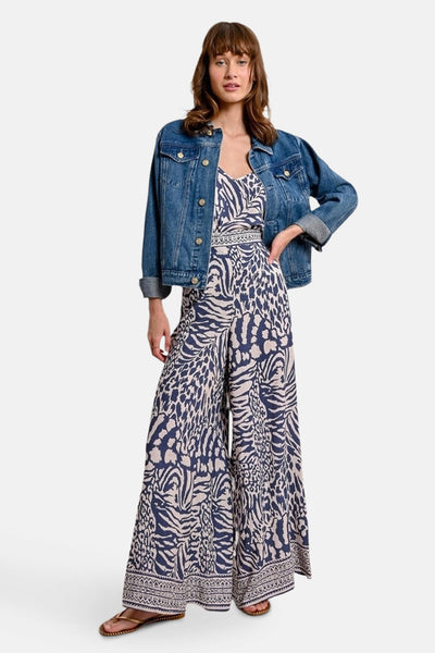 Pantalon bleu à motifs animaliers de Molly Bracken, porté avec une veste en jean et des sandales.
