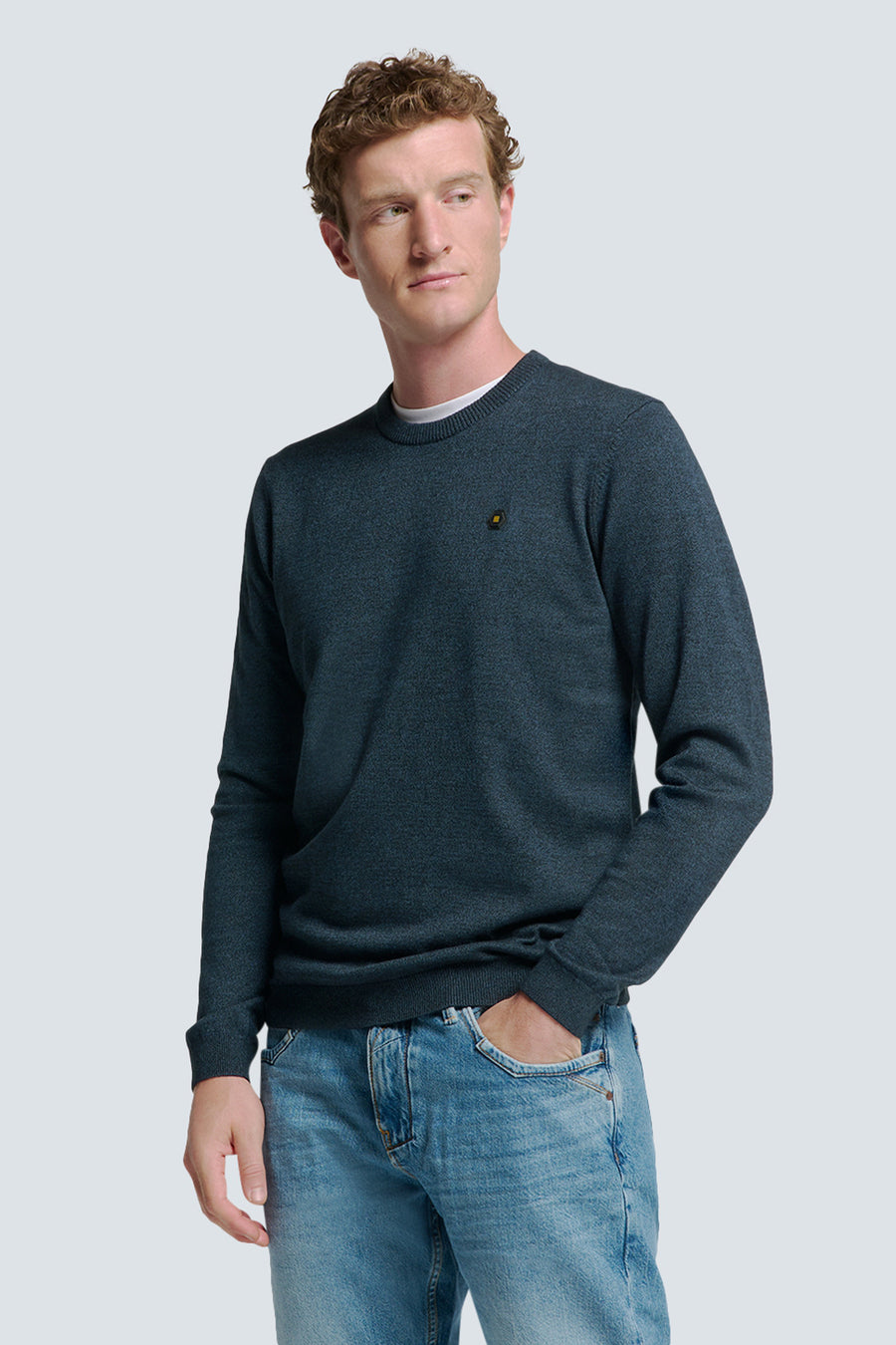 Pull à col rond bleu de NO EXCESS, porté avec un t-shirt blanc et un jean délavé.
