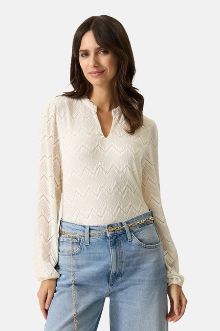 Blouse à manches longues écru de GARCIA, motif texturé chevron, portée avec une ceinture chaîne dorée et un jean taille haute.
