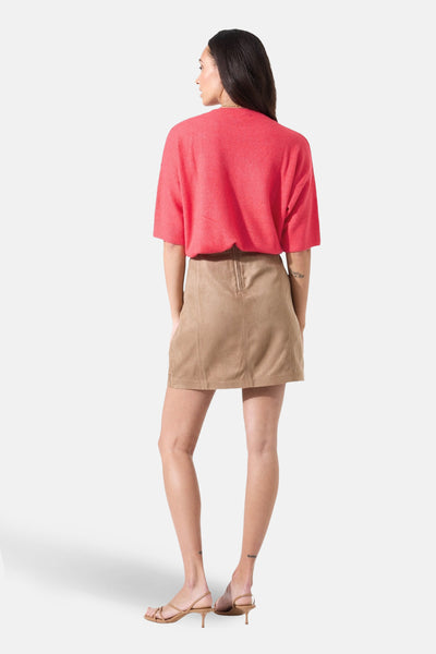 Pull à col rond rose de GARCIA, manches courtes, porté avec une jupe en daim et des sandales à talons.