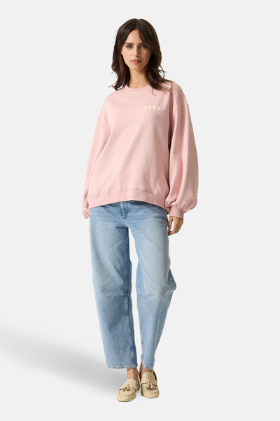Roze GARCIA sweatshirt met decoratieve opdruk, gedragen met een wijde jeans en beige kwastjesloafers.