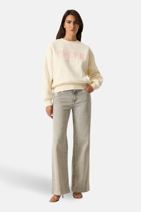 Sweat-shirt écru GARCIA avec motif « Amore » rose sur le devant, porté avec un jean et des sandales.