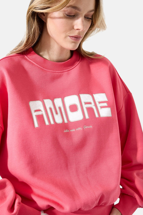 Sweat rose col rond de Garcia, avec l'inscription "Amore" en lettres blanches sur le devant.