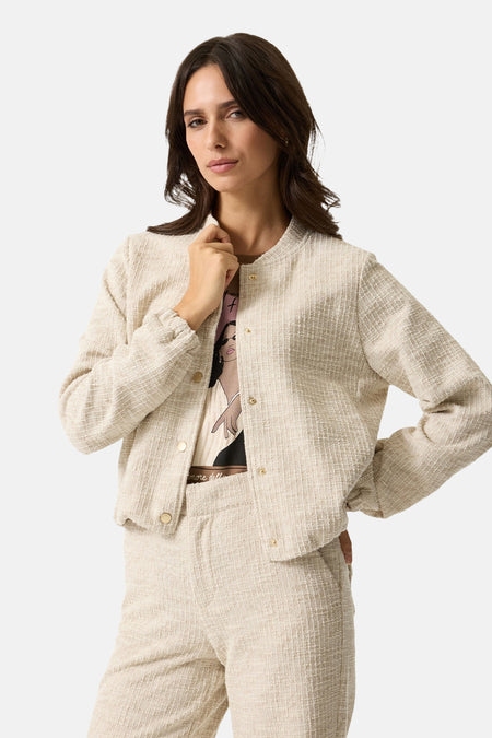 Veste courte beige de GARCIA, texturée avec des boutons dorés, portée avec un T-shirt imprimé et un pantalon assorti.