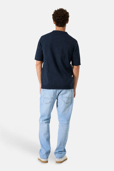 Polo à manches courtes bleu de GARCIA, vue de dos, porté avec un jean clair et des chaussures blanches.
