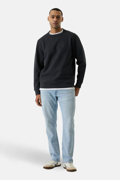 Pull gris GARCIA, avec un logo discret sur la poitrine, porté sur un t-shirt blanc et un jean clair.