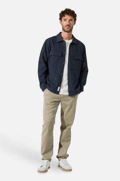 Chemise à manches longues bleu de GARCIA, avec poches poitrine et boutons, portée sur un t-shirt blanc et un pantalon beige.