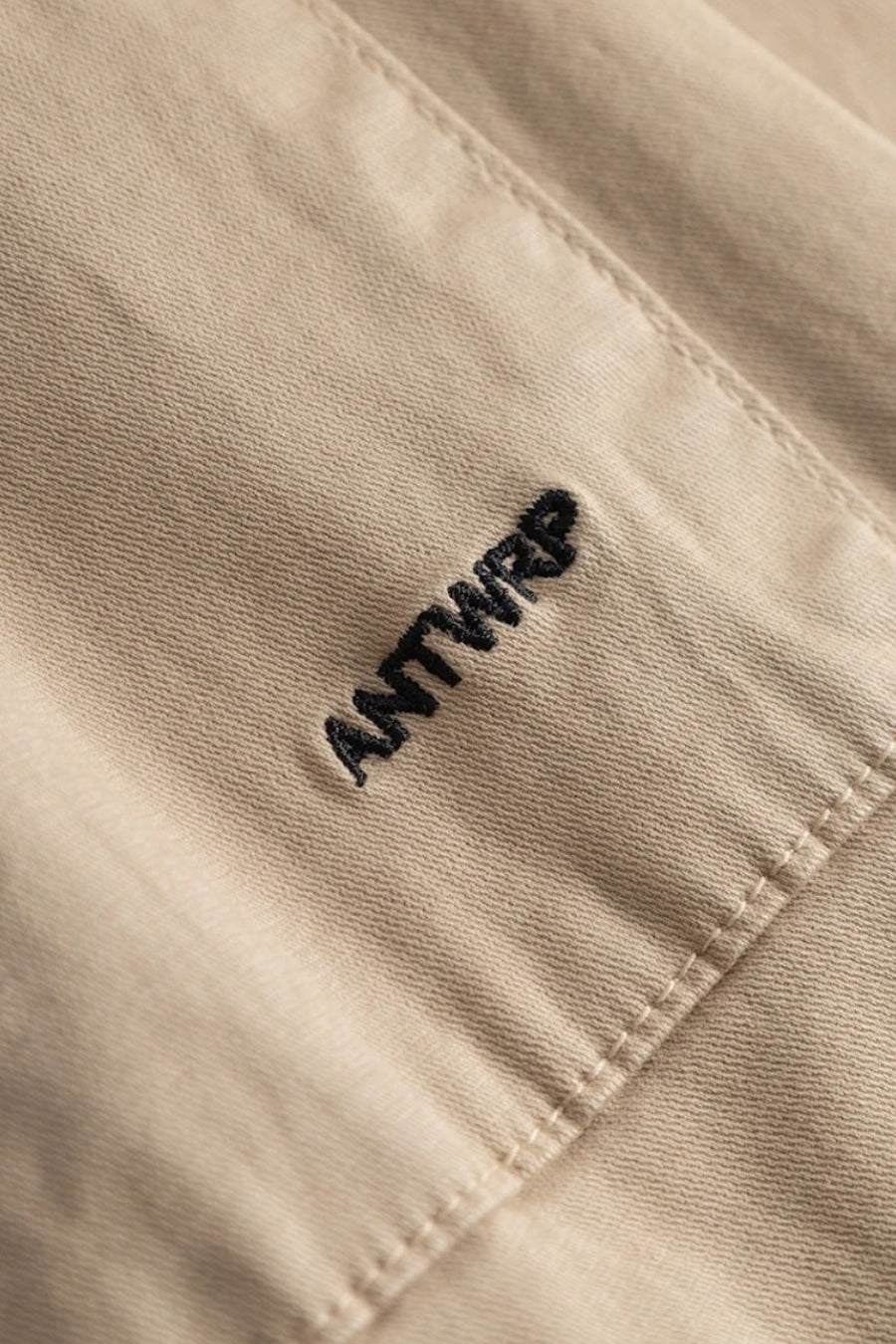 Pantalon beige de ANTWRP, avec une broderie du nom de la marque, détail de couture visible.