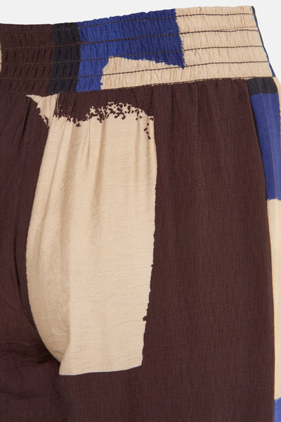 Multikleurige broek van AMELIE ET AMELIE, met elastische tailleband en abstract patchworkpatroon in bruine, beige en blauwe tinten.