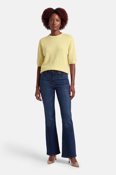 Gele rondehals trui van AMELIE ET AMELIE, korte mouwen, gedragen met een blauwe jeans en beige pumps.