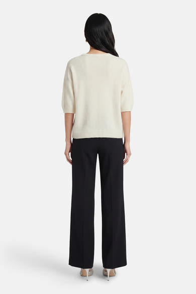 Ecru ronde hals trui van AMELIE ET AMELIE, korte mouwen, gedragen met een zwarte broek met hoge taille.