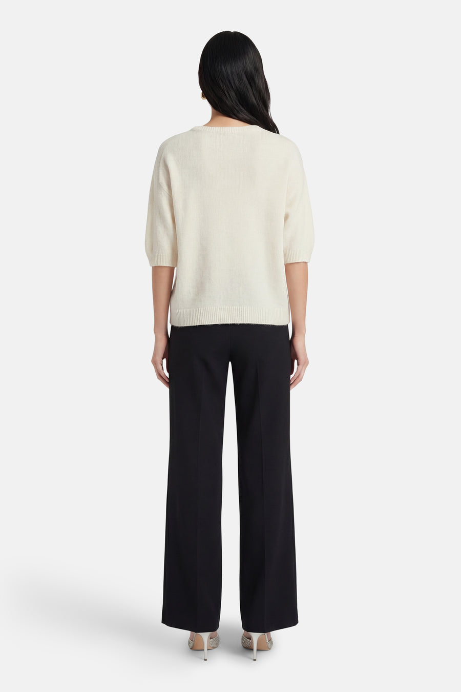 Ecru ronde hals trui van AMELIE ET AMELIE, korte mouwen, gedragen met een zwarte broek met hoge taille.