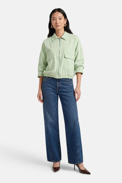 Gilet vert van AMELIE ET AMELIE, porté avec un jean et des escarpins marron.
