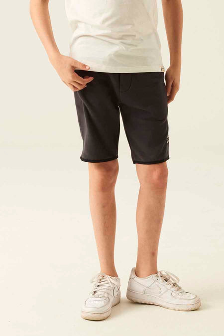 Gray cotton jogger shorts by [brand omitted] with side pocket, ribbed hem, worn with white t-shirt and sneakers, front view