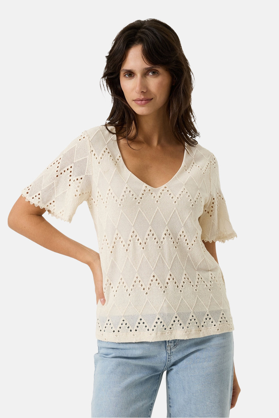Blouse écru à manches courtes de GARCIA, avec motif losanges ajouré et ourlet festonné, portée avec un jean bleu clair.
