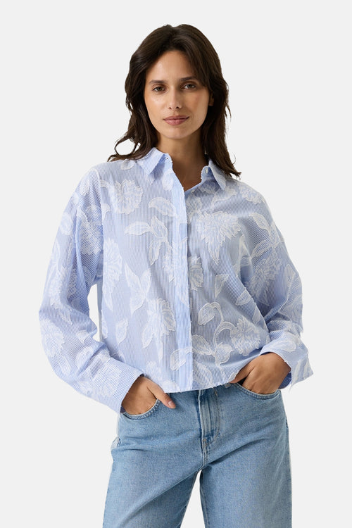 Chemisier bleu rayé de GARCIA, orné de motifs floraux blancs texturés, porté avec un jean décontracté.
