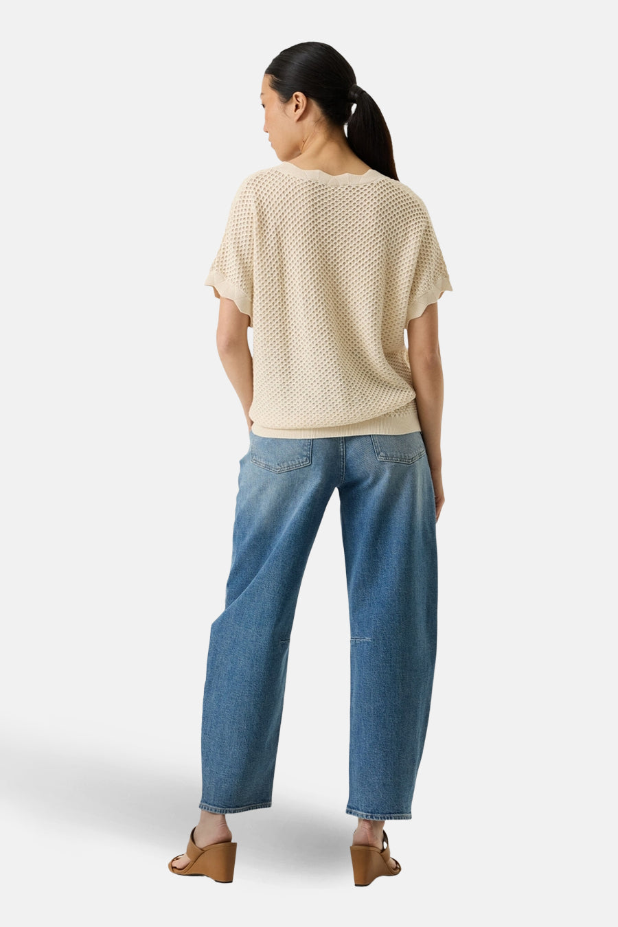 Beige gebreide trui met open structuur van GARCIA, gedragen met een wijde blauwe jeans en sleehak sandalen, achtergezicht.