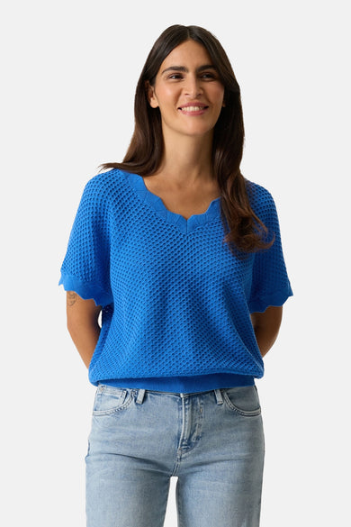 Pull bleu à col en V de GARCIA, en maille ajourée, porté avec un jean clair.