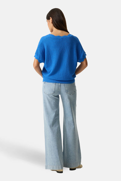 Pull bleu en maille par GARCIA, avec manches courtes à ourlet festonné, porté avec un jean taille haute.