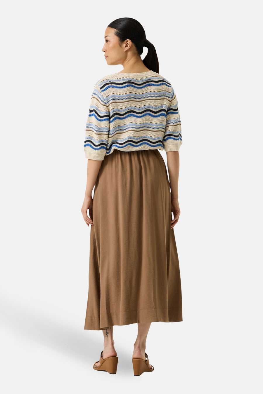 Pull multicolore col O de GARCIA, avec des motifs à rayures et des manches courtes, porté avec une jupe longue marron.