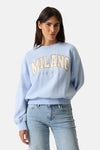 Sweat bleu à col rond de GARCIA, avec inscription "Milano" beige et pantalon en jean clair.
