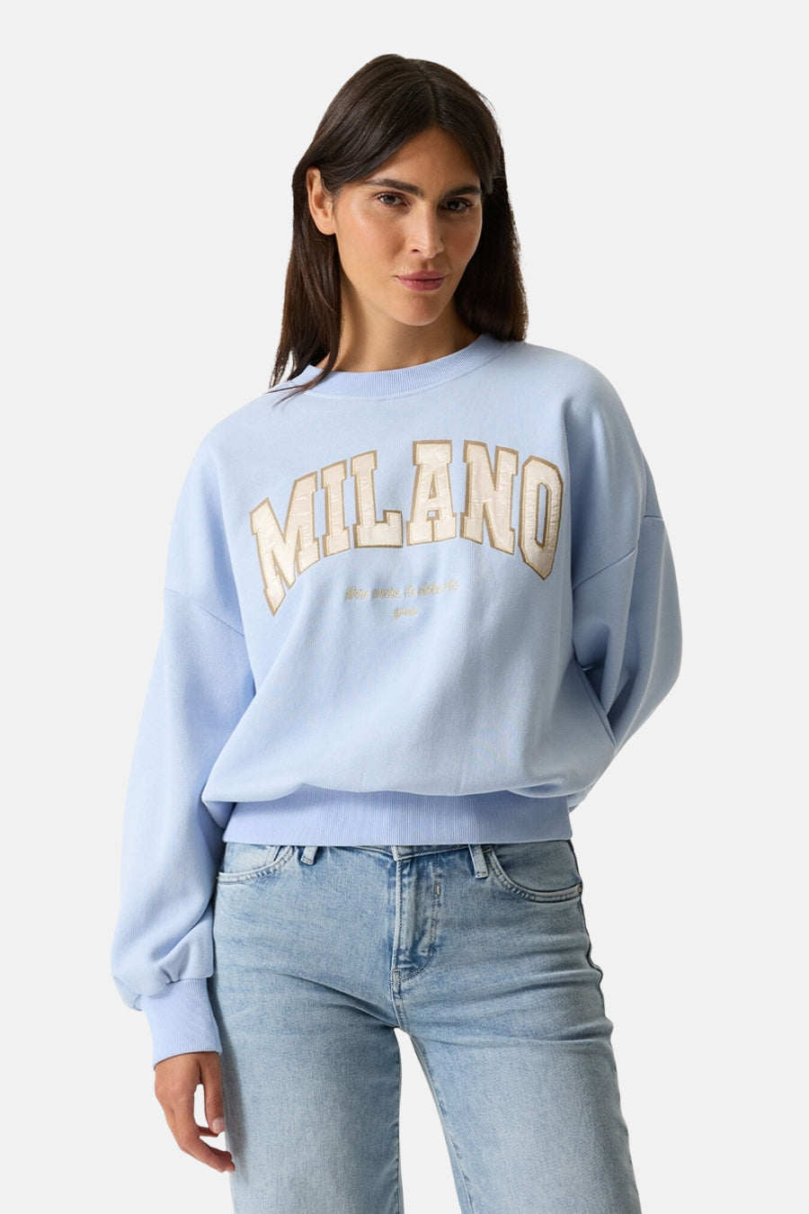 Sweat bleu à col rond de GARCIA, avec inscription "Milano" beige et pantalon en jean clair.

