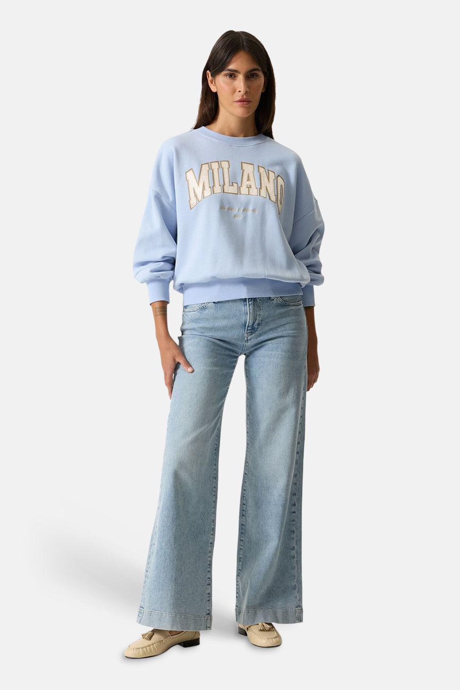 Sweat bleu de GARCIA avec inscription « Milano » et porté avec un jean ample et des chaussures à glands.
