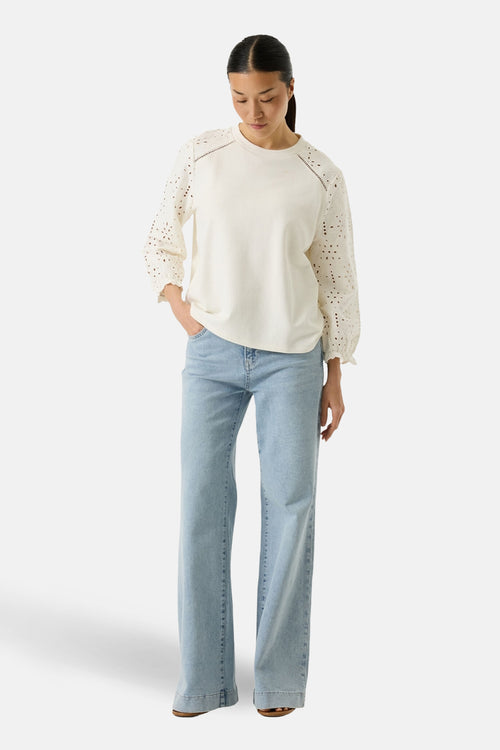 Sweat blanc de GARCIA, avec manches longues ajourées et pantalon en jean bleu clair.
