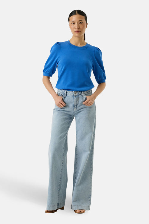 Sweat bleu col O par GARCIA, manches bouffantes, porté avec un jean large taille haute.
