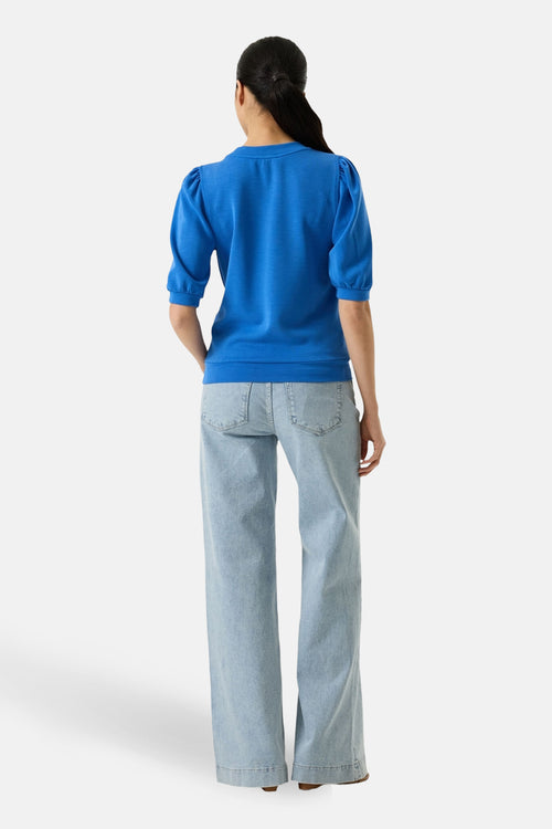 Sweat bleu à manches courtes de GARCIA, avec des jeans bleu clair à jambes larges.
