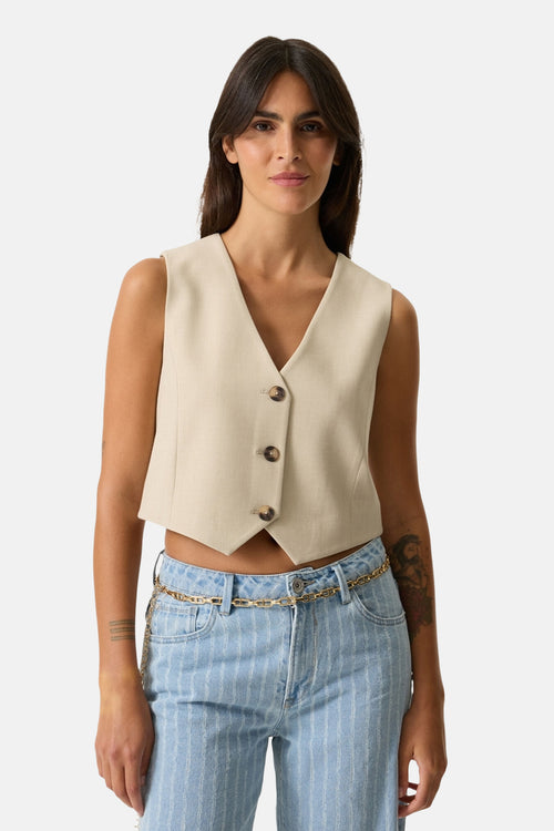 Blazer beige de GARCIA avec trois boutons, porté avec un jean rayé et une ceinture chaîne dorée.