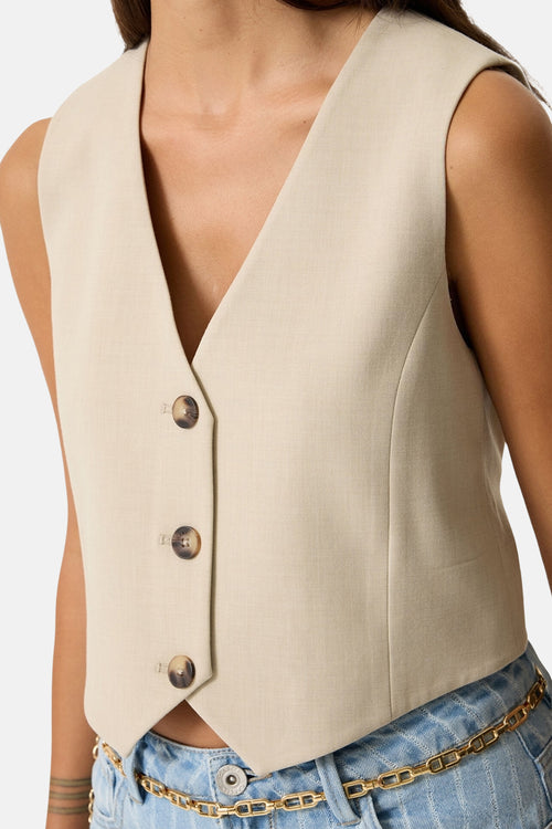 Blazer beige GARCIA avec une coupe ajustée, boutons marron, porté avec un jean et une ceinture dorée.