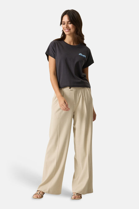 Pantalon de costume beige de GARCIA, à jambes larges, porté avec un t-shirt gris et des sandales dorées.