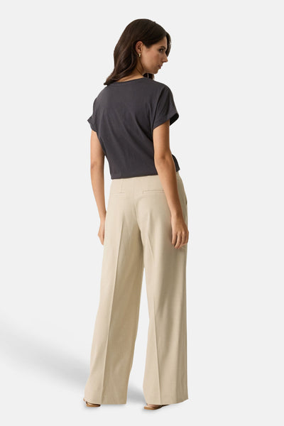 Pantalon de costume beige de GARCIA, coupe ample, avec une poche arrière passepoilée et ourlet tombant sur des sandales.