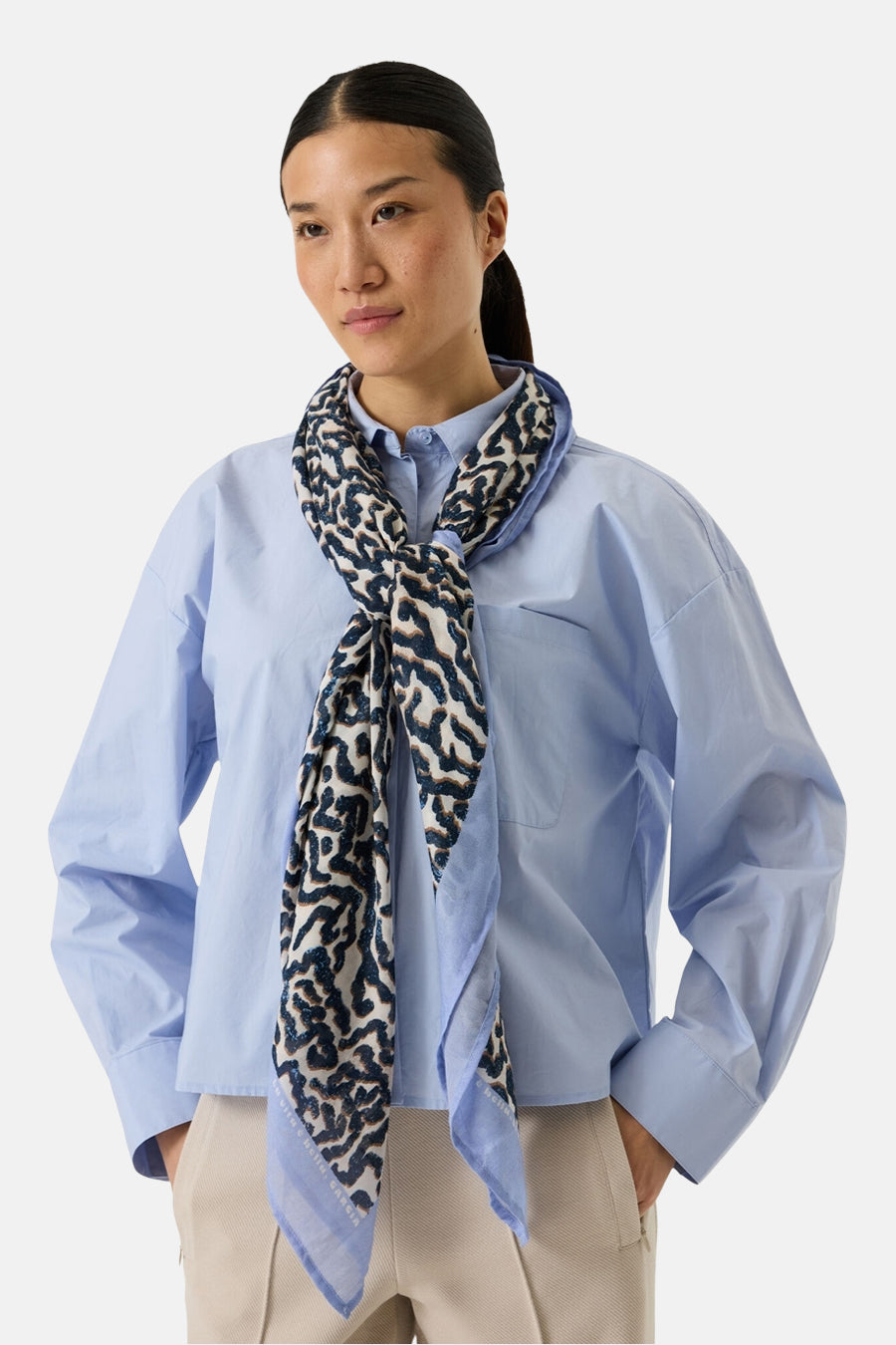 Foulard multicolore de GARCIA, à motif abstrait porté autour du cou avec une chemise bleu clair.
