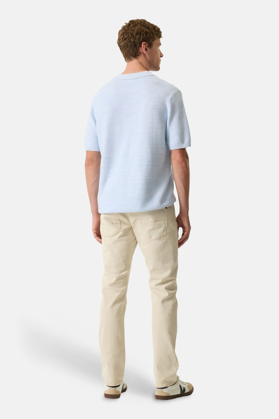 Polo blanc de GARCIA, manches courtes, porté avec un pantalon beige et des baskets.