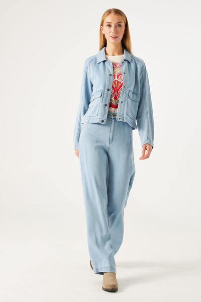 Veste en denim bleu clair de GARCIA, portée avec un pantalon assorti et des bottes en daim.