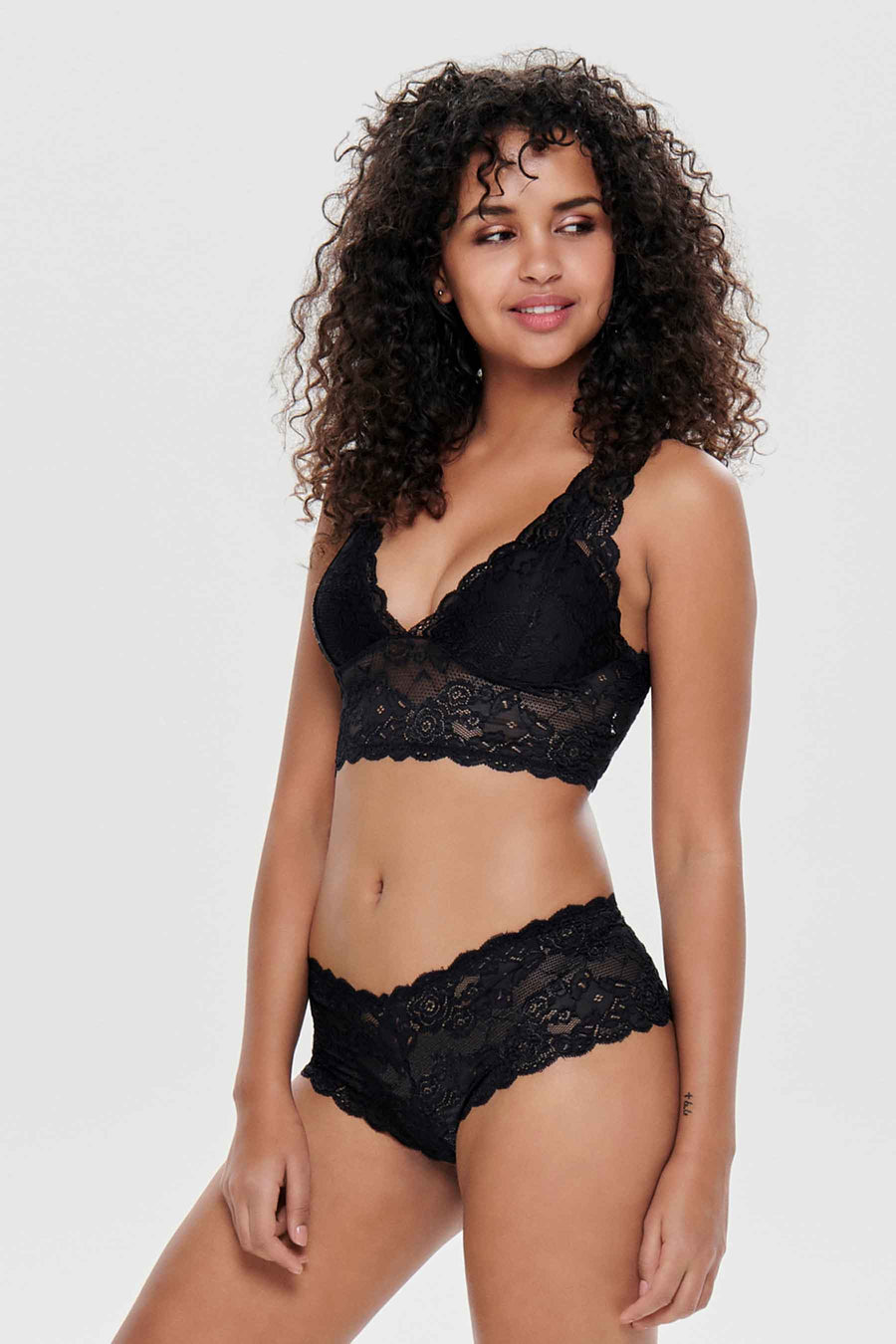 Soutien-gorge noir en dentelle de ONLY, porté par un modèle avec des cheveux bouclés.