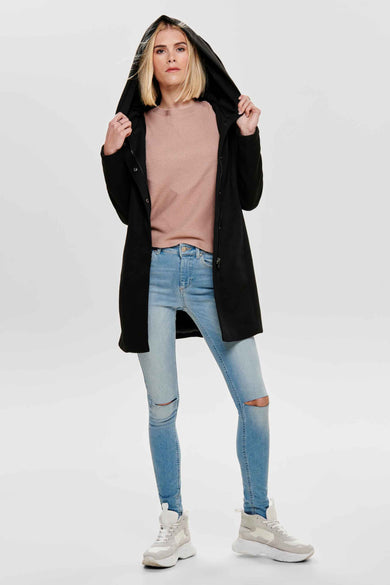 Veste longue noire de ONLY, portée avec un pull rose et un jean bleu déchiré.