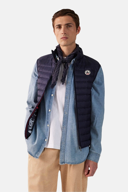Blauw mouwloos vest van JOTT, gedragen over een spijkerhemd en een wit T-shirt, met een beige broek.